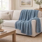 Dusty blue chunky knit throw draped over a chair to show its size