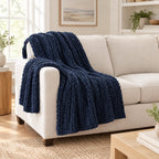 Navy chunky knit throw draped over a chair to show its size