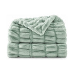 Sage green faux fur throw, folded product shot on a white background